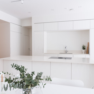 Kiiltävä valkoinen keittiö uppoutuu taustaansa